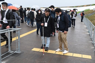 大屋根「リング」が枝分かれする地点で、点状の警告用ブロックを確認する佐木理人記者（中央左）＝大阪市此花区で2025年4月13日、大西岳彦撮影
