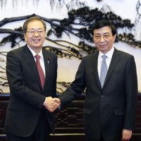 中国共産党序列4位の王滬寧政治局常務委員（右）と握手する公明党の斉藤鉄夫代表＝北京の人民大会堂で23日、共同