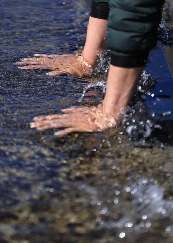 ウトロ漁港で海水に手を浸ける男性。男性の長男の小柳宝大さんは事故で行方不明となっている＝北海道斜里町で2025年4月23日午後2時7分、宮間俊樹撮影