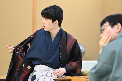 第83期名人戦第1局2日目の対局中に着ていた羽織を脱ぐ藤井聡太名人。内側には将棋の駒が描かれていた。右は挑戦者の永瀬拓矢九段＝東京都文京区のホテル椿山荘東京で2025年4月10日午前9時4分、手塚耕一郎撮影
