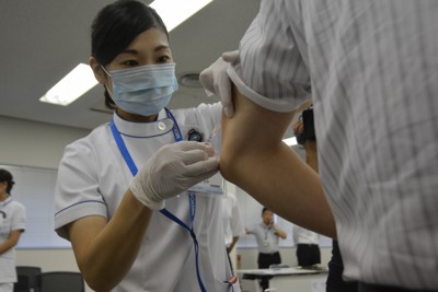 2016年には関西国際空港で働く従業員らがはしかに集団感染。ワクチン接種を受ける空港関係者（右）＝関西国際空港で2016年9月8日午後2時5分、井川加菜美撮影