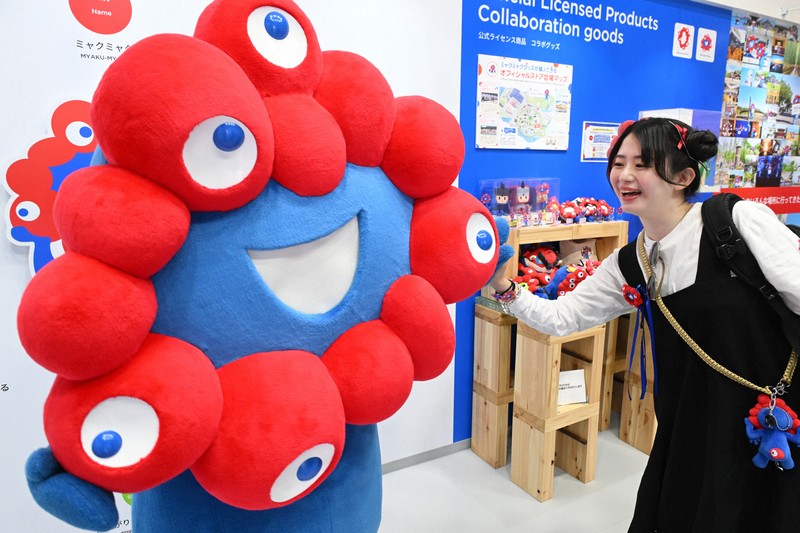 万博会場の「ミャクミャクハウス」で来場者とタッチを交わすミャクミャク＝大阪市此花区で2025年4月25日、大西岳彦撮影