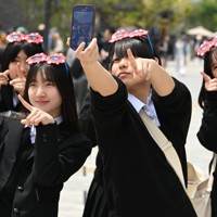 ミャクミャクグッズを身につけて記念撮影をする来場者＝大阪市此花区で2025年4月25日、大西岳彦撮影