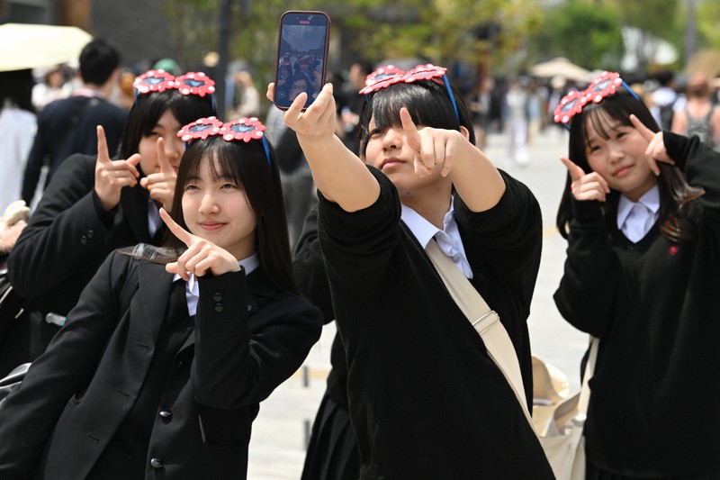 ミャクミャクグッズを身につけて記念撮影をする来場者＝大阪市此花区で2025年4月25日、大西岳彦撮影