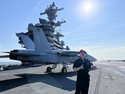 米空母「ジョージ・H・W・ブッシュ」の飛行甲板で、空母と戦闘機について説明する海軍担当者＝2025年4月30日、西田進一郎撮影