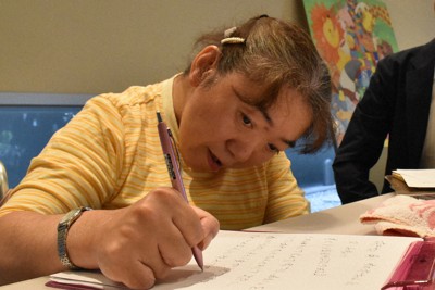 思うように動かない手でペンを執り懸命に思いを伝える古山知恵子さん＝新潟市中央区で2025年5月20日午前10時20分、戸田紗友莉撮影