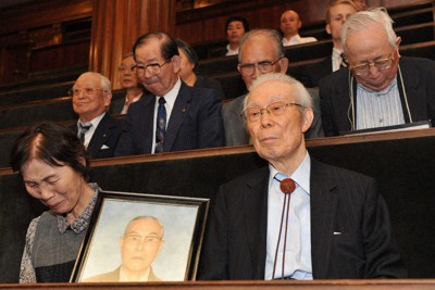 シベリア特措法が成立し、抑留被害者だった夫・恒雄さんの遺影を手に涙ぐむ松原政子さん（手前左）と、平塚光雄・全国抑留者補償協議会会長（手前右、いずれも故人）ら＝国会内で2010年6月16日、西本勝撮影