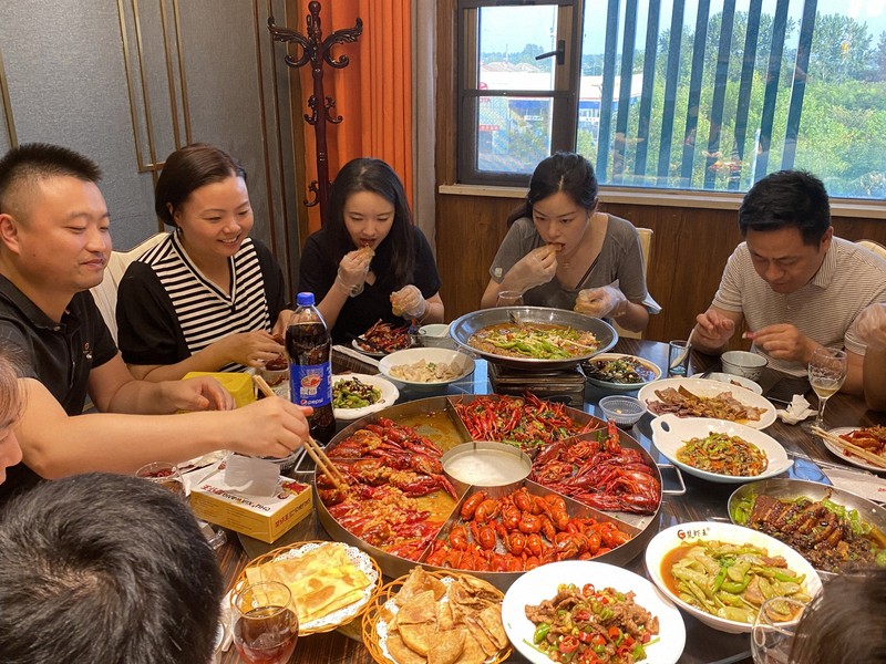 大皿を囲み、ザリガニ料理を味わう中国の人々＝中国湖北省潜江市で2022年7月14日午後6時38分、岡崎英遠撮影