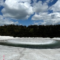 姿を現した「八幡平ドラゴンアイ」。目は全体の3分の1ほどに雪解け水がないが、瞳にあたる部分ははっきりしてきた＝秋田県仙北市の鏡沼で2025年5月28日午後、佐藤岳幸撮影