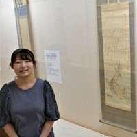 大田南畝が賛を寄せた絵を背景に「番組で親しんだ南畝の世界を深く味わえます」と話す谷川月彩学芸員＝愛媛県今治市の同市河野美術館で2025年6月5日、松倉展人撮影