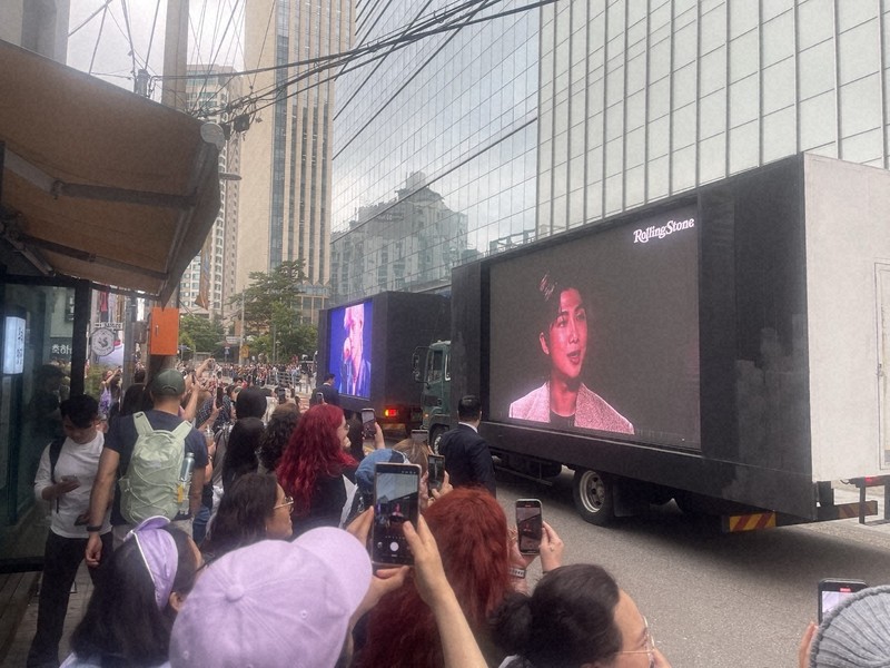 BTSのRMさんとVさんの除隊を祝い、所属するHYBE本社前に集まったファンら。2人を映し出した大画面のトラックが通過する度に歓声が上がった＝ソウル市内で2025年6月10日午前、堀山明子撮影