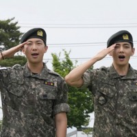 兵役を終え、敬礼するBTSのRMさん（左）とVさん＝韓国北部・春川で2025年6月10日、AP