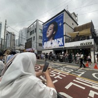 BTSのRMさんとVさんの除隊を祝い、所属するHYBE本社前に集まったファンら。奥の建物に掲げられたのは6月11日除隊予定のジミンさんの写真＝ソウル市内で2025年6月10日午前、堀山明子撮影