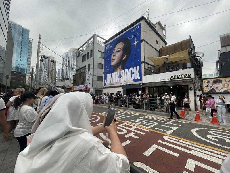 BTSのRMさんとVさんの除隊を祝い、所属するHYBE本社前に集まったファンら。奥の建物に掲げられたのは6月11日除隊予定のジミンさんの写真＝ソウル市内で2025年6月10日午前、堀山明子撮影