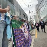 BTSのRMさんとVさんの除隊を祝い、所属するHYBE本社前に集まったファンら。警備員が車道を確保しようと巡回していた＝ソウル市内で2025年6月10日午前、堀山明子撮影