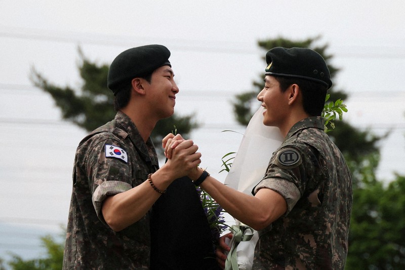 兵役を終え、手を握り合うBTSのRMさん（左）とVさん＝韓国北部・春川で2025年6月10日、ロイター