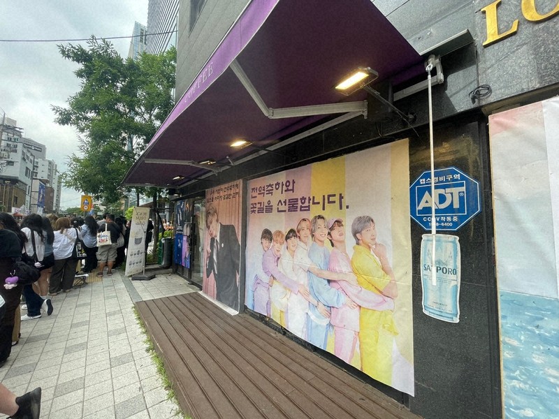 BTSが所属するHYBE本社周辺のカフェに掲げられた、メンバーの除隊を祝うポスター＝ソウル市内のHYBE本社近くで2025年6月10日午前、堀山明子撮影