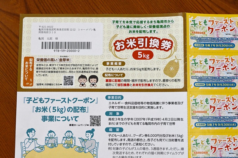 京都府亀岡市が市内の子どもに送る「お米引換券」と8000円分のクーポン券の見本＝2025年6月2日午後2時42分、南陽子撮影