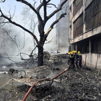 航空機の墜落現場で消火作業に当たる消防隊員ら＝インド西部アーメダバードで2025年6月12日、AP