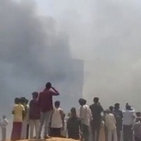 航空機の墜落後、立ち上る煙を眺める人々＝インド西部アーメダバードで2025年6月12日、AP