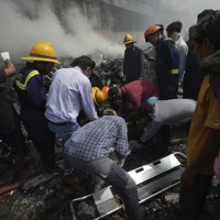 航空機の墜落現場で救助作業をする人たち＝インド西部グジャラート州アーメダバードで2025年6月12日、AP