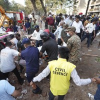 航空機の墜落現場から犠牲者を運び出す人たち＝インド西部グジャラート州アーメダバードで2025年6月12日、AP