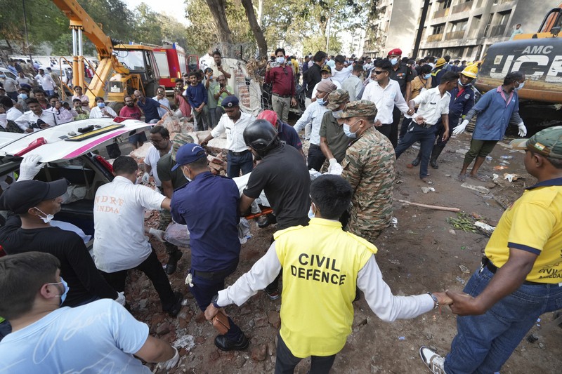 航空機の墜落現場から犠牲者を運び出す人たち＝インド西部グジャラート州アーメダバードで2025年6月12日、AP