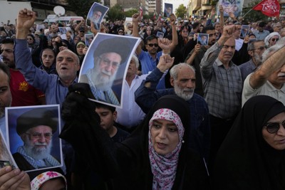 イラン最高指導者ハメネイ師のポスターを掲げ、米軍の攻撃に抗議するデモの参加者＝2025年6月22日、AP