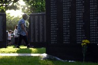 花を手に、祖父ら親族の名前が刻まれた「平和の礎」を訪れた新垣清子さん（75）＝手前。「戦後80年たっても沖縄には米軍の基地があって、今の子供たちやその先の世代を思うと歴史が繰り返されないか心配さ」＝2025年6月23日午前6時15分、北山夏帆撮影