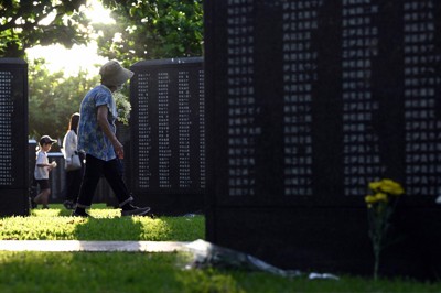 花を手に、祖父ら親族の名前が刻まれた「平和の礎」を訪れた新垣清子さん（75）＝手前。「戦後80年たっても沖縄には米軍の基地があって、今の子供たちやその先の世代を思うと歴史が繰り返されないか心配さ」＝2025年6月23日午前6時15分、北山夏帆撮影