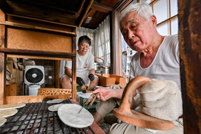 せんべいを焼く岩立光央さん（手前）。奥は長男の規史さん＝埼玉県草加市で2025年6月23日、渡部直樹撮影