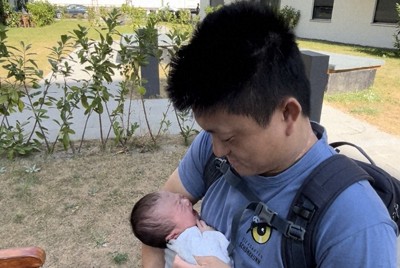 自宅アパートの中庭で、生後1週間ほどの娘を腹巻きに入れる諏訪正晃さん＝ベルリンで2024年9月7日、五十嵐朋子撮影