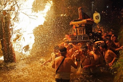 キリコ祭りの先陣を切って催された「あばれ祭」。たいまつから落ちる火の粉を浴びながら川を進む酒垂神社の神輿＝石川県能登町で、岩本一希撮影