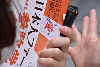 参政党候補者の演説を聴き、ビラを持ちながら手をたたく支持者＝東京都中央区で2025年7月3日午前10時49分、春増翔太撮影