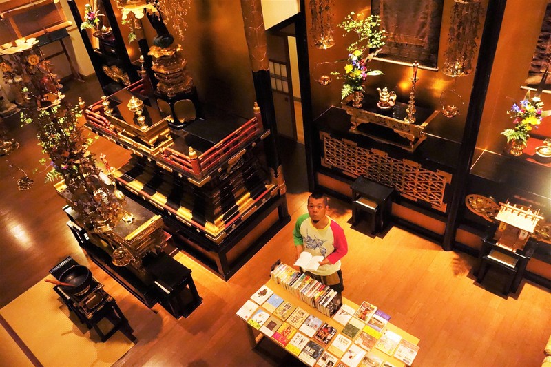 専立寺の本堂内に並ぶ書籍と日野岳史乗住職＝盛岡市で5月16日午後8時6分、高橋昌紀撮影