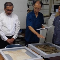 被爆で亡くなった豊島長生さんの学生服とシャツの説明を永町謙さん（中央）から聞くペイマン・セアダット駐日イラン大使（左）。右は上田紘治さん＝東京都八王子市内で2025年7月2日、野倉恵撮影