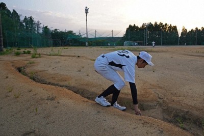 能登半島地震で練習場所のグラウンドに入ったひび割れに落ちたボールを拾う野球部員＝石川県珠洲市で2025年7月9日午後6時46分、岩本一希撮影