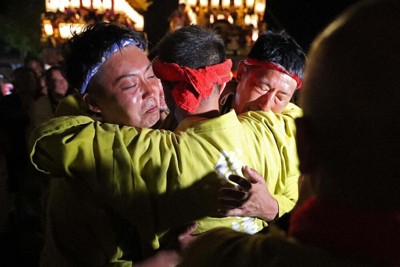 飯田燈籠山祭りが終わり、各地区の取締と抱き合う総取締役の助則保章さん＝石川県珠洲市で