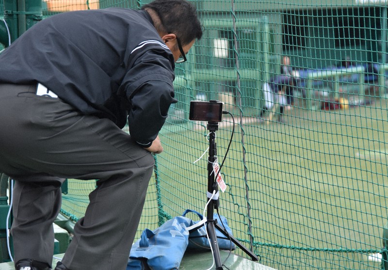 試合前にビデオ検証用のスマートフォンを設定する仙台六大学野球連盟の菊地正志審判＝仙台市の東北福祉大野球場で2025年5月24日、長宗拓弥撮影