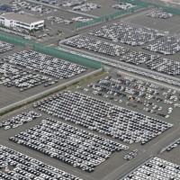 日産自動車九州苅田工場に隣接する港湾エリアに並ぶ完成した乗用車。奥は輸出車の運搬船＝福岡県苅田町で2025年4月10日午前10時32分、本社ヘリから上入来尚撮影