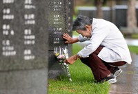 Nagasaki A-bomb survivor Tomoko Oshiro offers flowers at the Cornerstone of Peace in Itoman, Okinawa Prefecture, where her father Chiyu Bise's name is engraved, on June 25, 2025. Her mother Sachiko's name is also engraved a short distance away. (Mainichi/Shinnosuke Kyan)