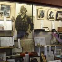 神風特攻記念館で、関行男大尉の出撃前の写真（中央）などの展示品を紹介する奉賛会の上野陽一副会長＝西条市で2025年7月8日午後3時58分、狩野樹理撮影