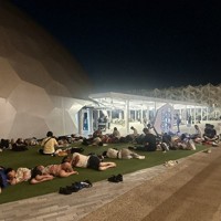 地下鉄の運転見合わせで帰宅が難しくなり、電力館前の芝生で横たわる来場者たち＝2025年8月14日午前3時半ごろ（万博会場を訪れた女性提供）