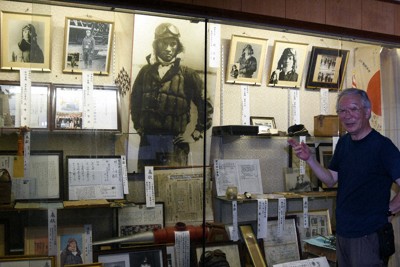 神風特攻記念館で、関行男大尉の出撃前の写真（中央）などの展示品を紹介する奉賛会の上野陽一副会長＝愛媛県西条市で、狩野樹理撮影