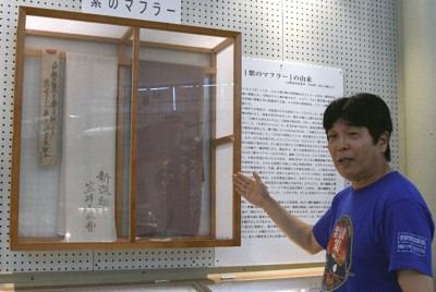 紫電改展示館には、笠井智一さんから寄贈された紫のマフラーが展示されている。紹介するのは永元一広館長＝愛媛県愛南町で、狩野樹理撮影