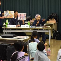 子どもたちに、自身で描いた被爆の絵を見せながら話す服部道子さん（正面右）ら＝埼玉県蕨市中央4の市福祉・児童センターで2025年8月7日、萩原佳孝撮影