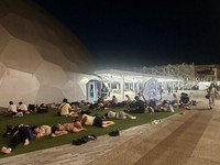 This photo provided by an Expo visitor shows people lying down on the lawn in front of the Electric Power Pavilion at around 3:30 a.m. on Aug. 14, 2025.