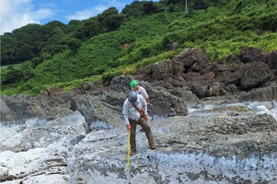 吉浦海岸で隆起した岩を測量する安江健一・富山大准教授＝石川県輪島市門前町七浦地区で、東栄一撮影