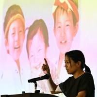 スクリーンに映し出された亡き子どもたちの前で命の大切さを伝える大上かおりさん＝福岡市東区の博多高で2025年7月11日、矢頭智剛撮影
