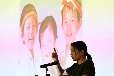 スクリーンに映し出された亡き子どもたちの前で命の大切さを伝える大上かおりさん＝福岡市東区の博多高で2025年7月11日、矢頭智剛撮影